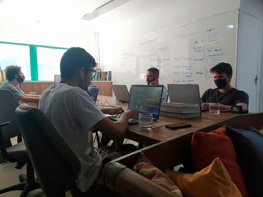 SIX team working around a table, with planning on the whiteboard